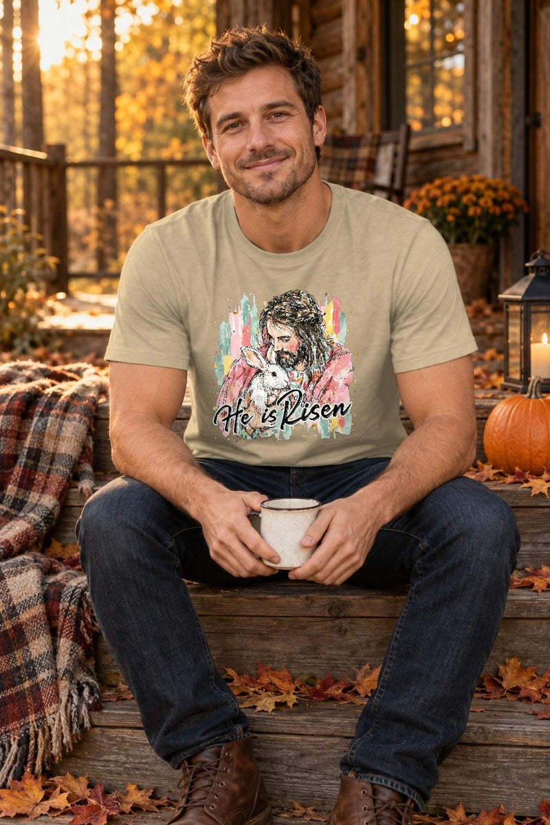 Christliches Oster T-Shirt „He Is Risen“ – Jesus hält ein weißes Häschen im …