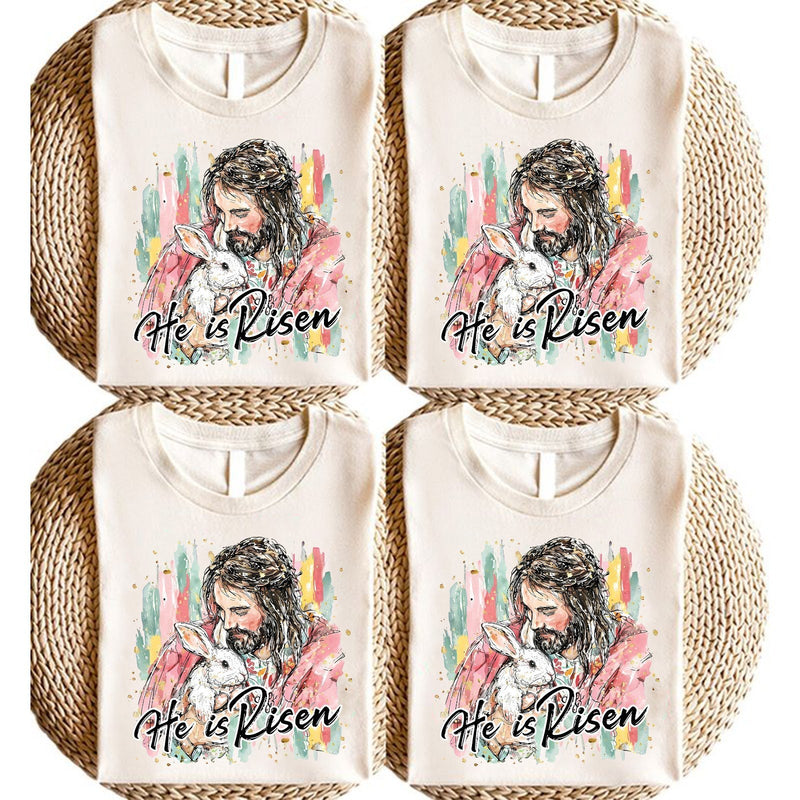 Christliches Oster T-Shirt „He Is Risen“ – Jesus hält ein weißes Häschen im …