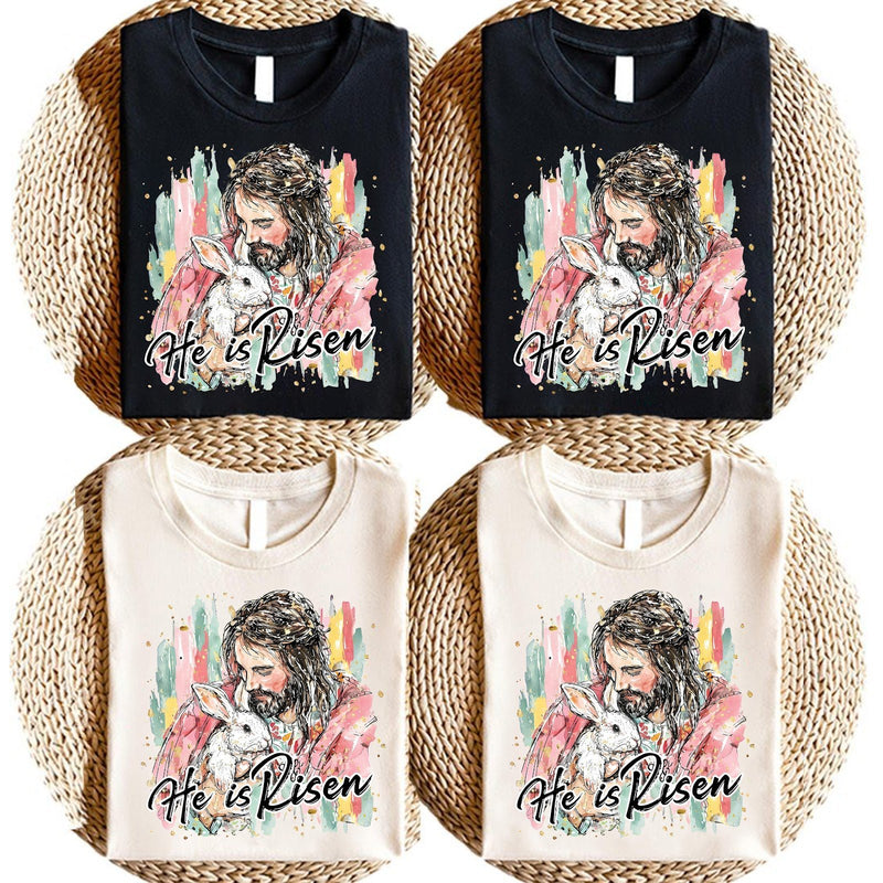 Christliches Oster T-Shirt „He Is Risen“ – Jesus hält ein weißes Häschen im …